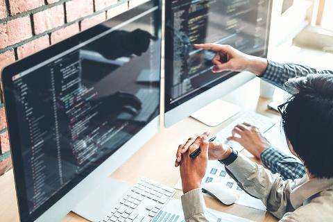 man coding in office on two screens