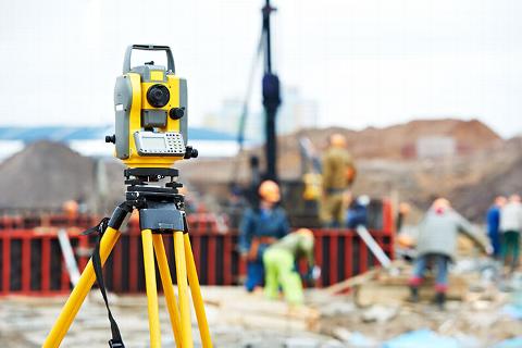 surveying equipment on building site with workers in the background