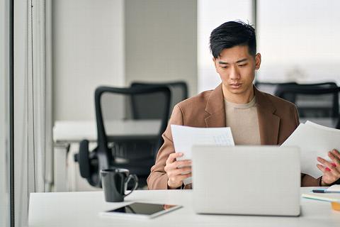 accountant looking over paperwork in office with laptop and coffee