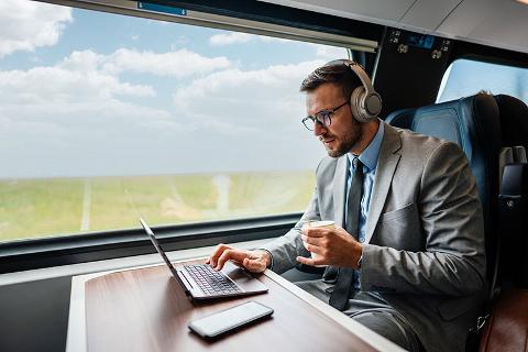 Business man sitting on train working on laptop